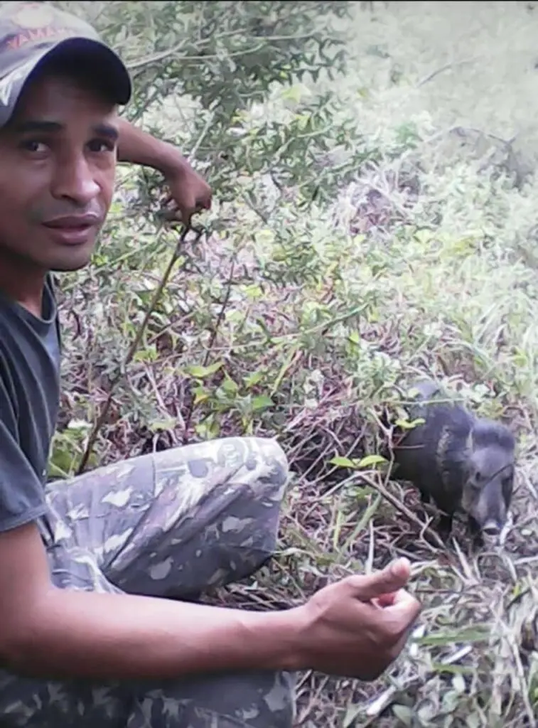Photo of a man with a wild animal on the ground beside him in Serra Bonita reserve, Brazil