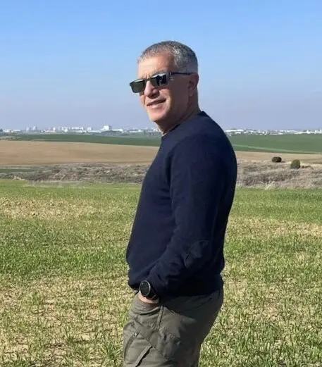 Man standing in a green field, wearing sunglasses.