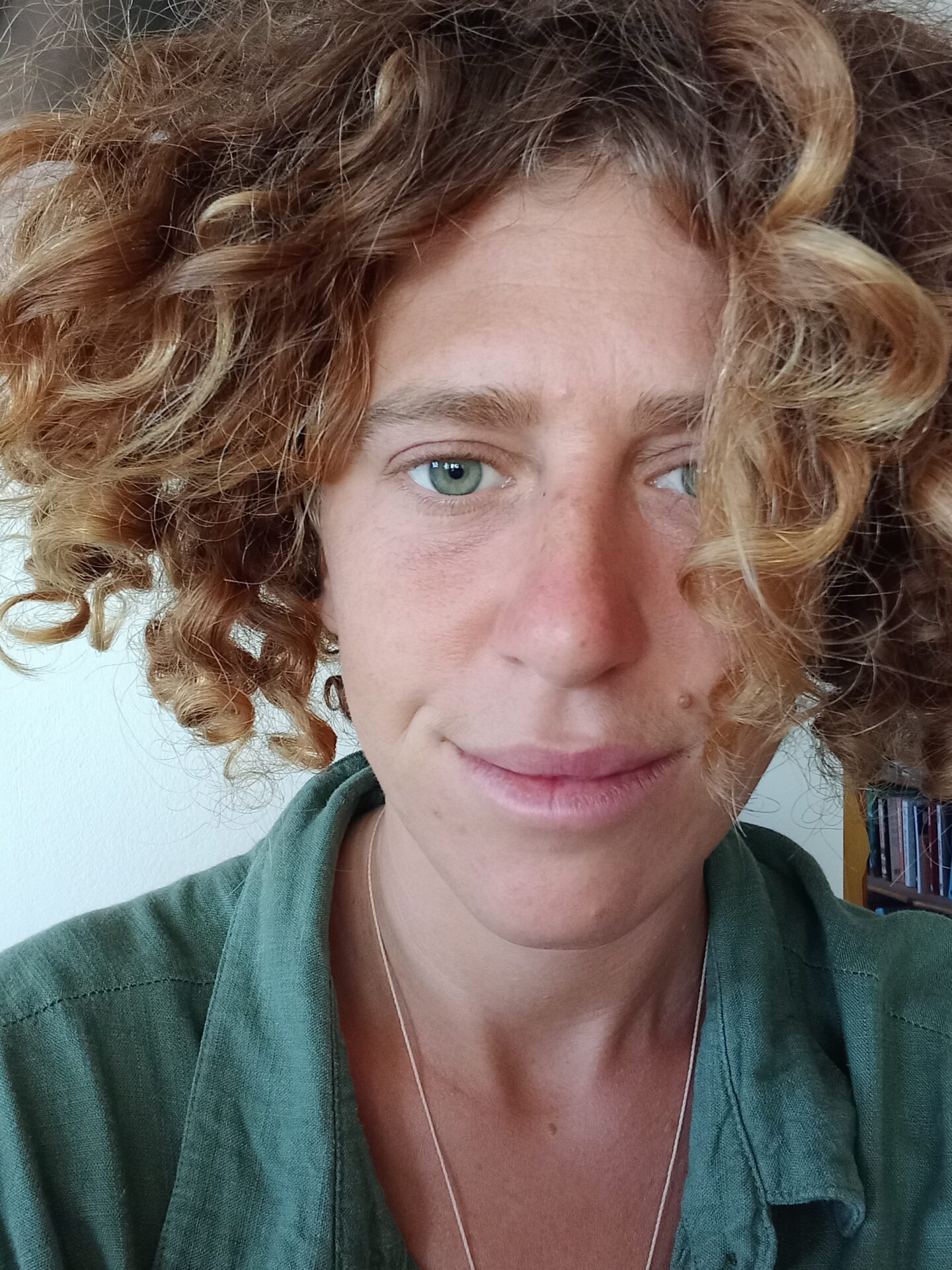 Portrait of a white woman with light brown curly hair, wearing a green shirt.